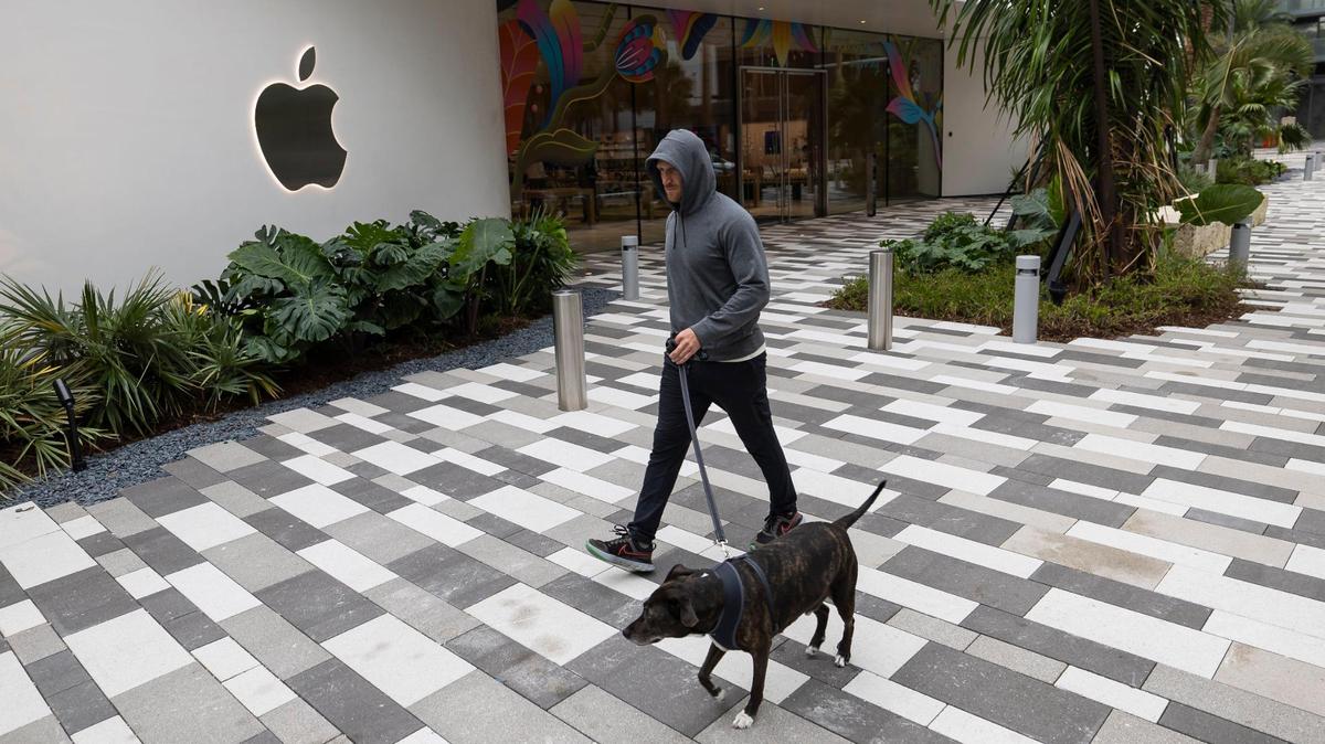 Nick Giuffrida and his dog, Luke, walk past the new Apple Miami Worldcenter store on Wednesday, Jan. 22, 2025, in downtown Miami, Fla. Apple is set to open its newest store in downtown Miami on Friday, featuring a dedicated pickup area and a biophilic garden.