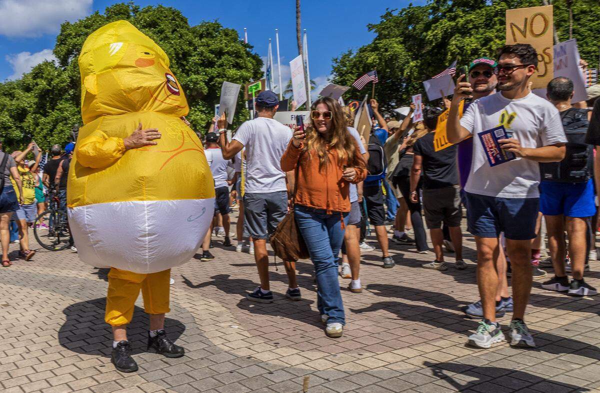 A person wearing an inflatable costume depicting President Donald Trump was among a crowd of protesters at the Miami-Torch of Friendship in downtown Miami during the “No Kings” anti-Trump protests taking place nationwide and all across South Florida on Saturday, Oct. 18, 2025.