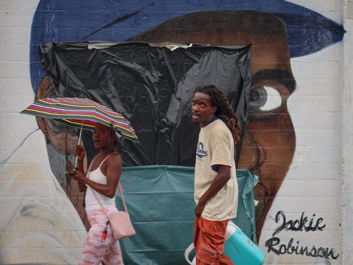 Passers-by walk in front of the Jackie Robinson mural after it was defaced with a swastika and Jim-Crow era racial epithet and covered with plastic on Tuesday, June 3, 2025 at Dorsey Park in Miami, Florida.