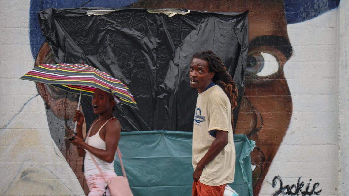 Passers-by walk in front of Jackie Robinson mural, the first black to integrate the Major League Baseball in 1947, after it was defaced with a hate crime with swastika and Jim-Crow era racial epithet and covered with plastic on Tuesday, June 3, 2025 at Dorsey Park in Miami, Florida.