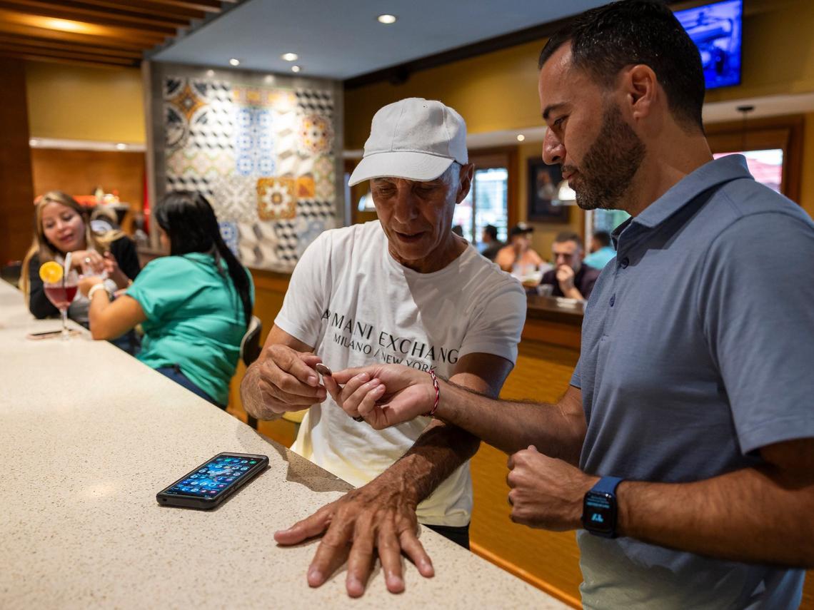 Latin Cafe 2000 owner Eric Castellanos, right, gifts Gilberto Fajardo a Celia Cruz quarter.