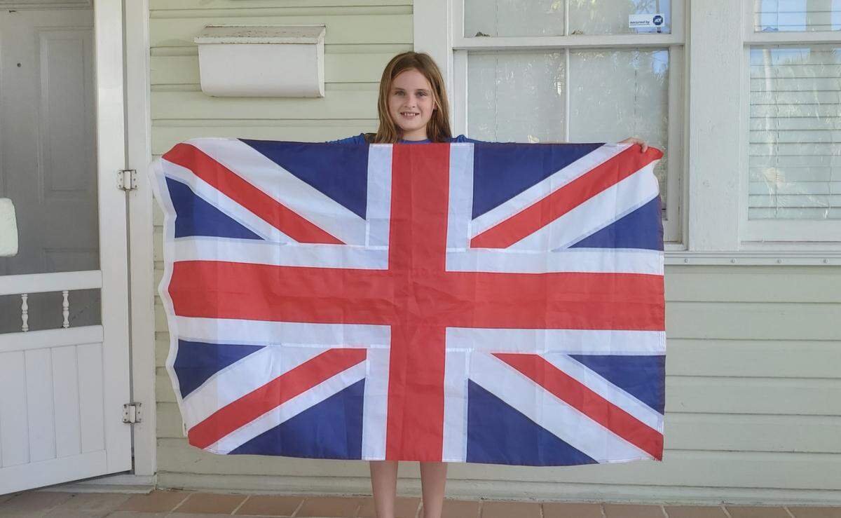 Ryah Bushey, 11, of Key West, holds the British flag her father Fred Bushey found on the ground near the Southernmost Point buoy on Sept. 18, 2022. A man had lowered the flag and walked off with it earlier that day.