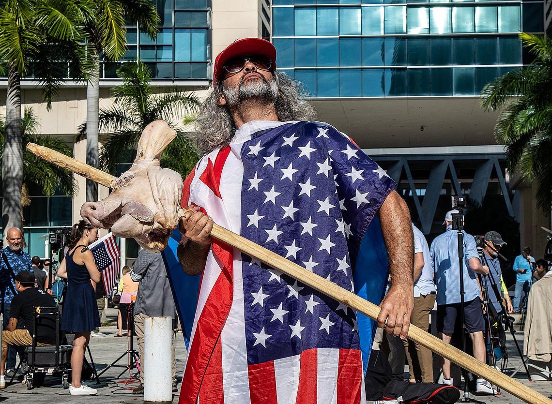 Osmany Estrada, holding a pig’s head on a stick in front of the Miami federal courthouse on Tuesday, June 13, 2023, says he’s ‘a smart Cuban’ who can’t support former president Donald Trump because he supports democracy and views Trump as anti-Democratic. .