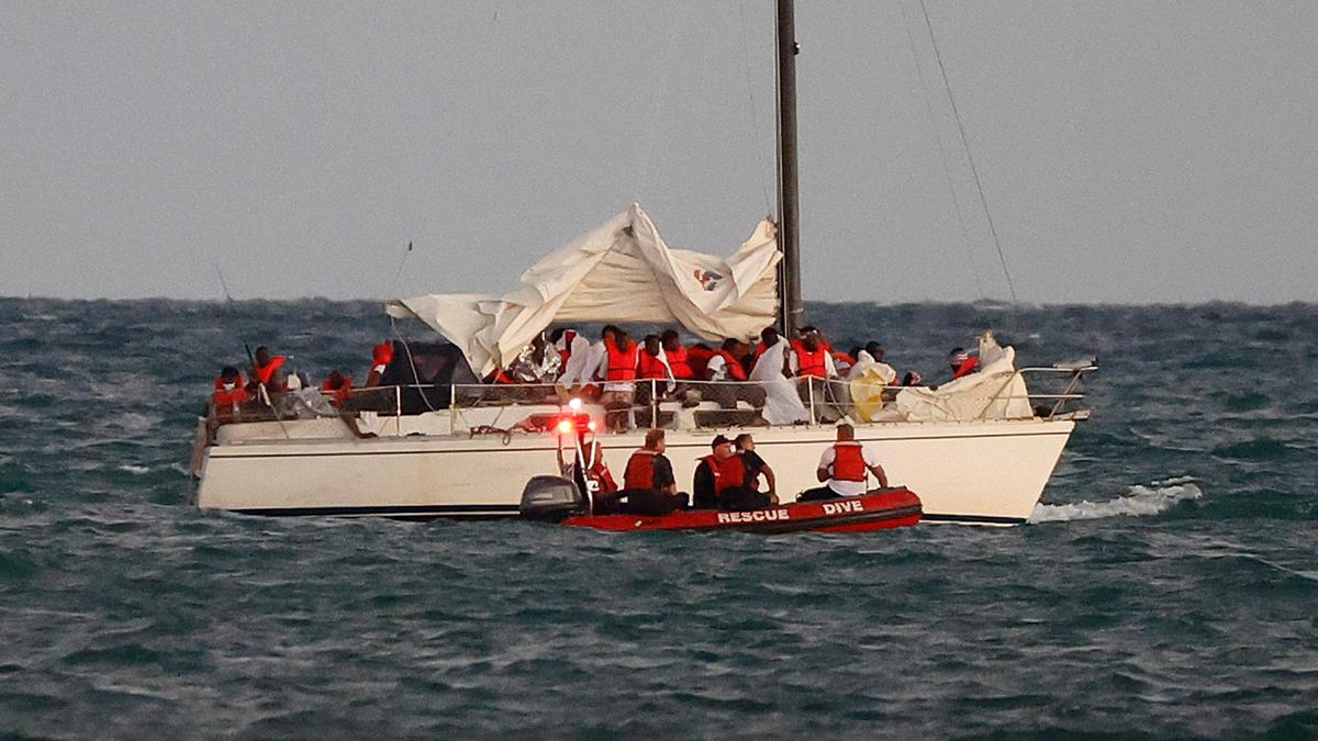 Miembros de la Guardia Costera se detienen junto a un velero que transporta a un gran grupo de migrantes frente a Virginia Key, cerca de Key Biscayne, Florida, el jueves 12 de enero de 2023. La llegada de migrantes ha provocado un aumento de las inscripciones en las escuelas públicas de Miami-Dade, especialmente alumnos procedentes de Cuba, Haití, Nicaragua y Venezuela.