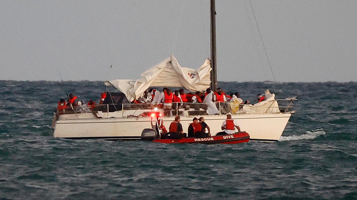 U.S. Coast Guard members pull up alongside a sailboat carrying a large group of migrants off Virginia Key near Key Biscayne, Florida, on Thursday, Jan. 12, 2023. The influx of migrants has caused a surge in student enrollment in Miami-Dade County public schools, particularly among students from Cuba, Haiti, Nicaragua and Venezuela.
