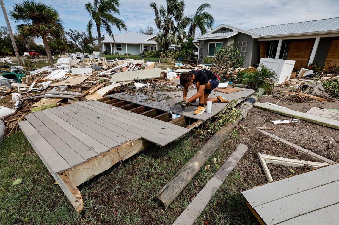 In an attempt to access a broken water line, Mike Giard, 16, removes boards from a wood deck that washed up onto his front yard during Hurricane Milton at New Point Comfort in Englewood, Florida on Thursday, October 10, 2024.