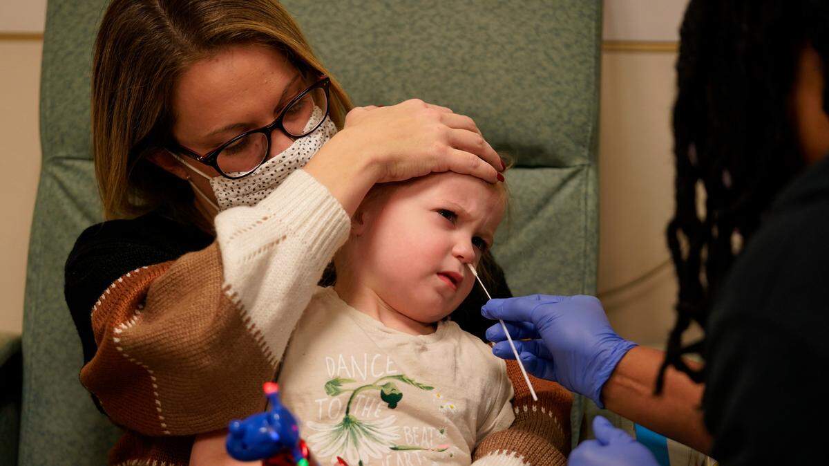 In this stock photo, Tara Carpenter holds her daughter Alyssa Carpenter, 3, as research nurse Michelle Harris give her a COVID-19 test during a followup visit at Children’s National Hospital in Washington, Monday, Feb. 28, 2022.