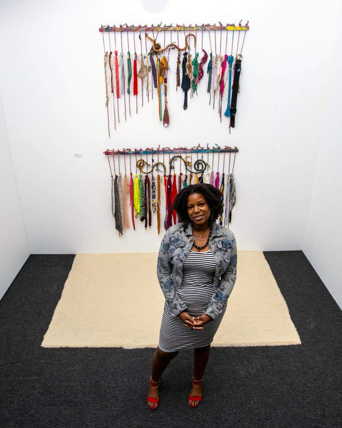 Artist Amber Robles-Gordon strikes a pose in front of her artwork entitled ‘At The Altar: Dance of the Serpents’ at the Art Prizm Fair during Art Basel in the Design District neighborhood of Miami, Florida, on Tuesday, November 29, 2022