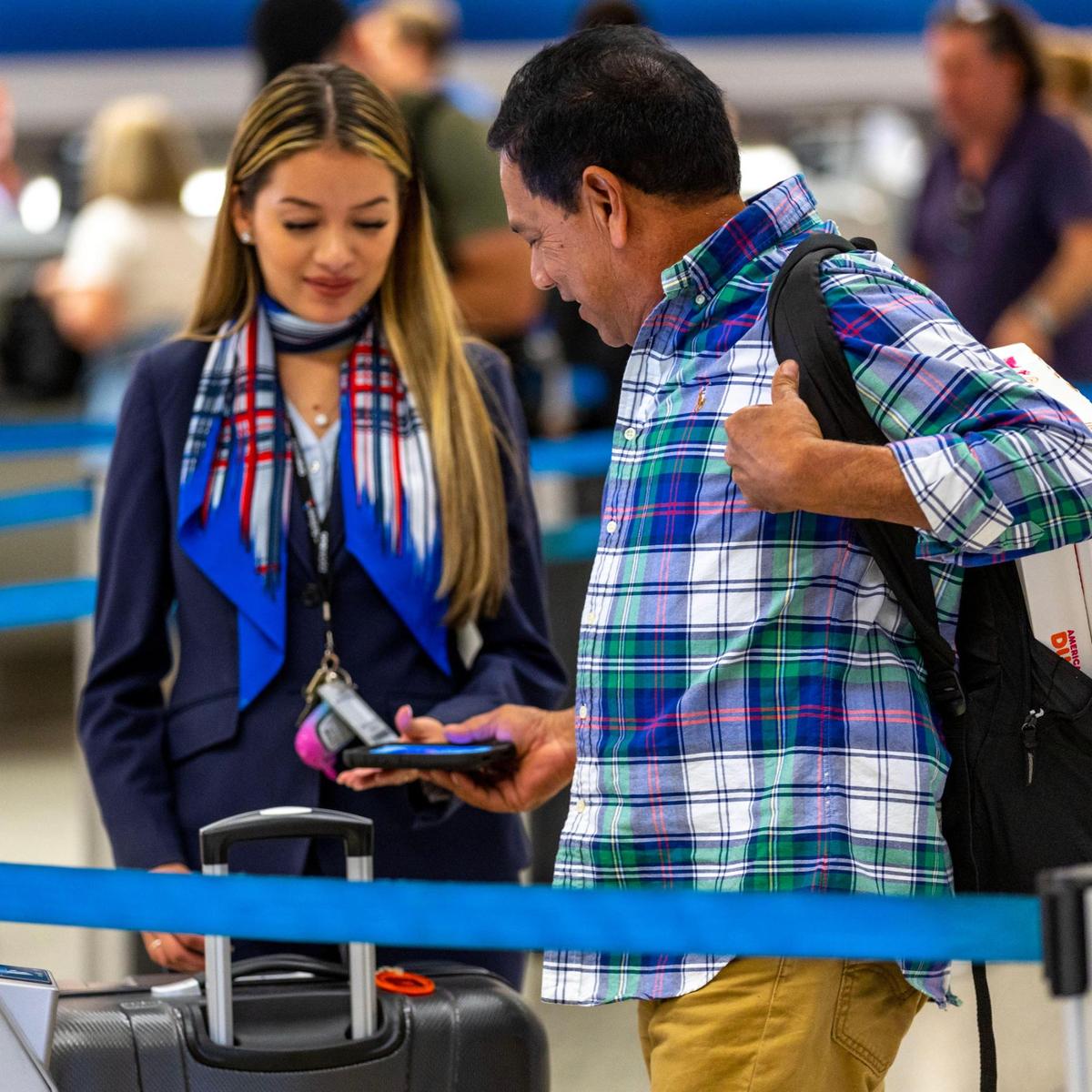 A traveler is assisted by airport staff as he checks in for a flight at Miami International Airport on Wednesday, Nov. 23, 2022.