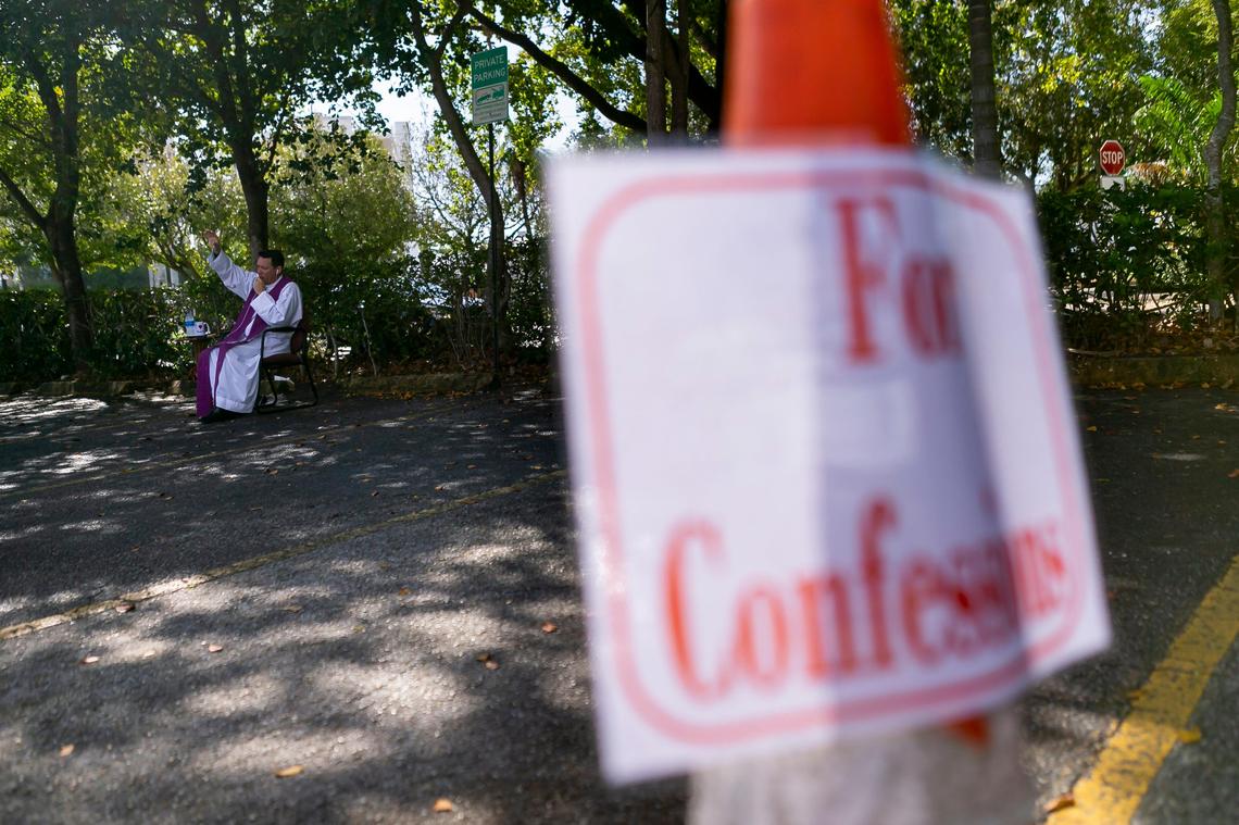 Father Richard Vigoa, the administrator of St. Augustine Church, talks with a churchgoer for a drive-thru confession in Coral Gables, Florida on Saturday, March 21, 2020. Due to COVID-19, churches have had to use technology and different ideas to help reach their parishioners.