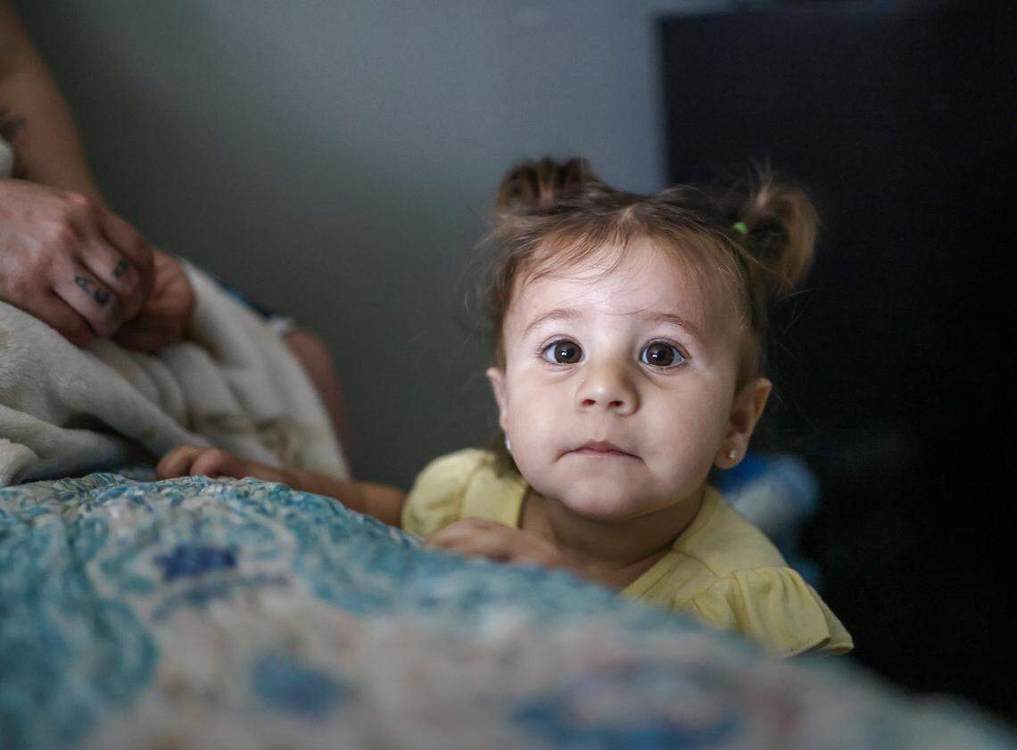 Itchel Perez, 1, right, plays plays her her sister at the edge of the bed while staying at Ernesto Motel after an attempt to self-deport stalled when their travel documents were taken at the border several years ago while seeking asylum in the United States on Thursday, April 2, 2026, in Miami, Florida.