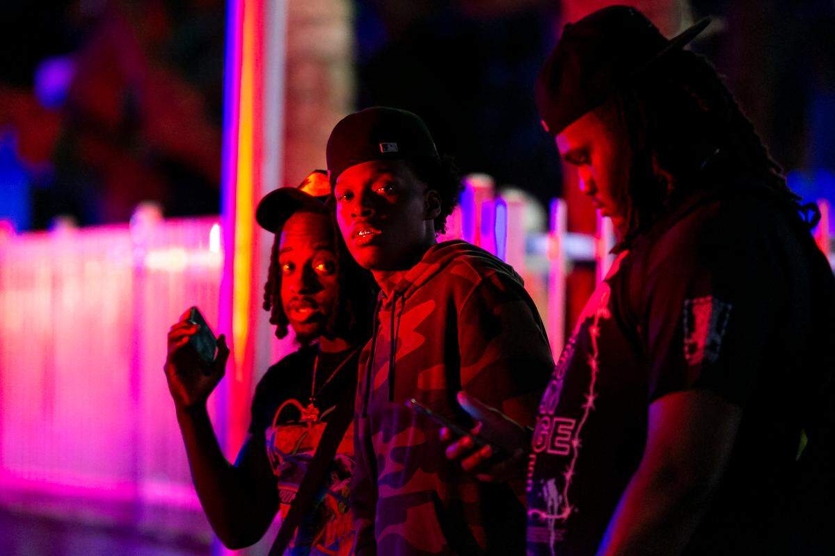People visit Ocean Drive near 10th Street as police officers patrol nearby in Miami Beach, Florida on Friday, March 25, 2022. City officials imposed a midnight curfew and forced stores to stop selling alcohol after 6 p.m. The restrictions were set in place after two shootings in Miami Beach the weekend before caused city officials to announce a “state of emergency.”