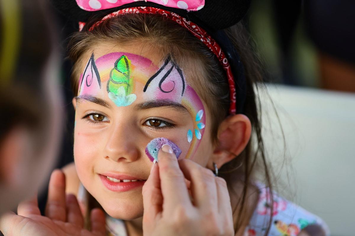 Teresa Ghanj, de 5 años, permanece inmóvil mientras el artista Ahrid Hannaley trabaja en la cara de un unicornio durante la inauguración de la parte este del Doral Central Park en 3005 NW 92nd Ave. en Doral, Florida, el lunes 26 de agosto de 2024.