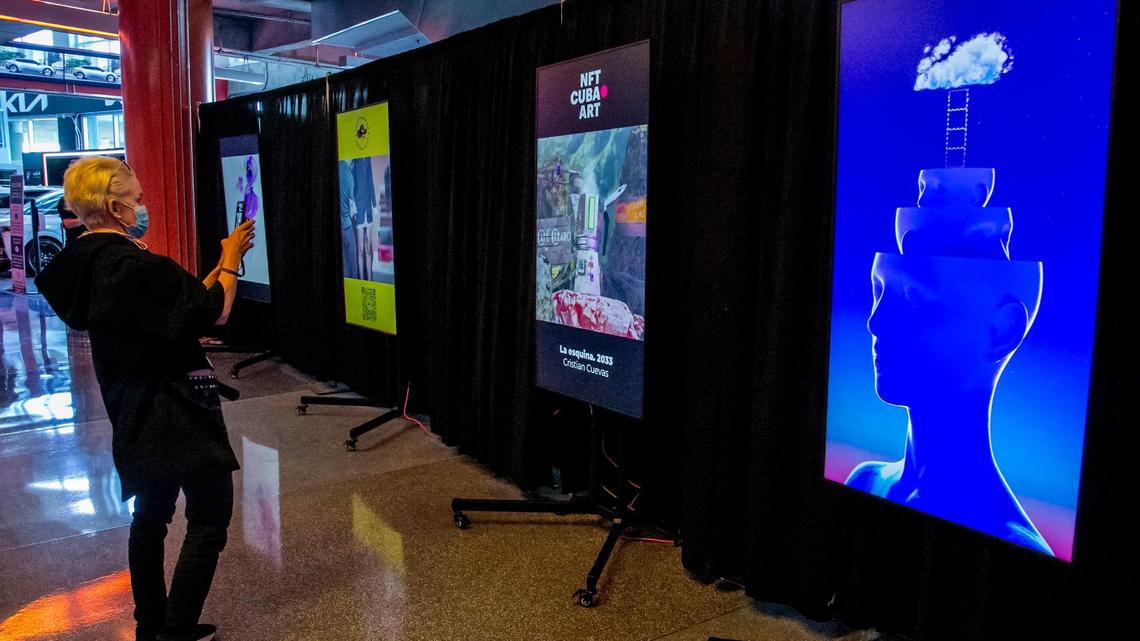 Local Miami artist Erin Parish photographs some NFTs on display at the NFT BZL event at FTX Arena in Miami on Nov. 30, 2021.