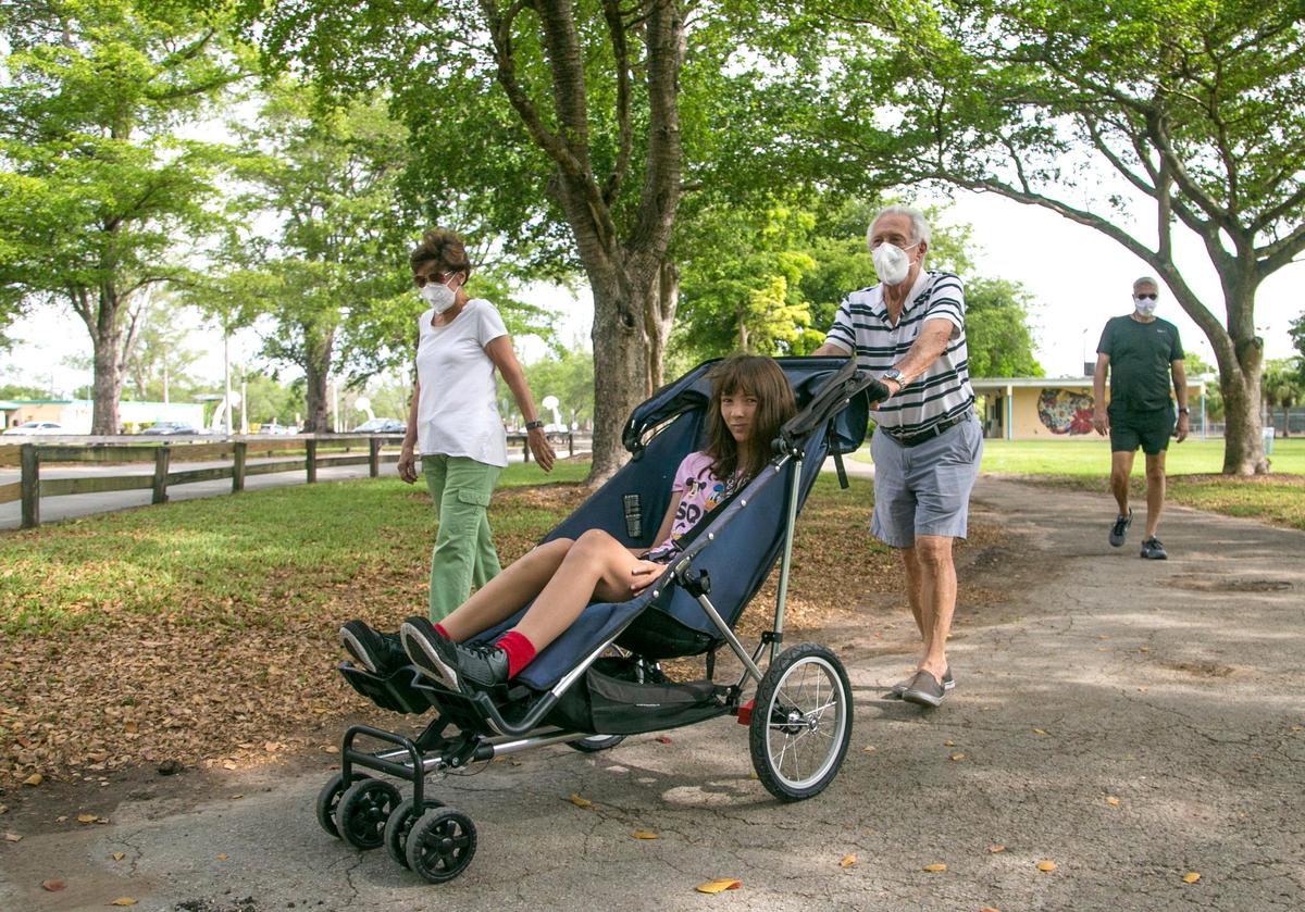 Maria Deribeaux and Gustavo Deribeaux walk their granddaughter Madison Deribeaux, 18, while walking through Tropical Park. Miami-Dade County lifted its park closure orders due to COVID-19 on April, 29, 2020.