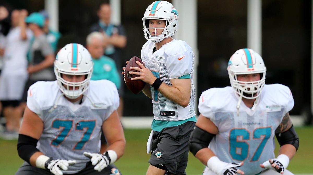 Miami Dolphins quarterback Ryan Tannehill (17) looks down field behind offensive lineman Jesse Davis (77) and Daniel Kilgore during a drill at the Miami Dolphins practice last Friday.