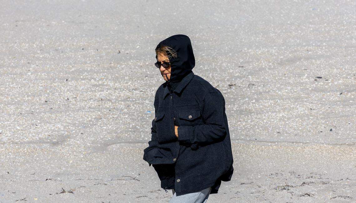 A woman walks along the beach bundled up against the cold in Sunny Isles Beach, Fla., on Sunday, Feb. 1, 2026. Miami-area temperatures dipped into the 30s, the coldest in more than 15 years.