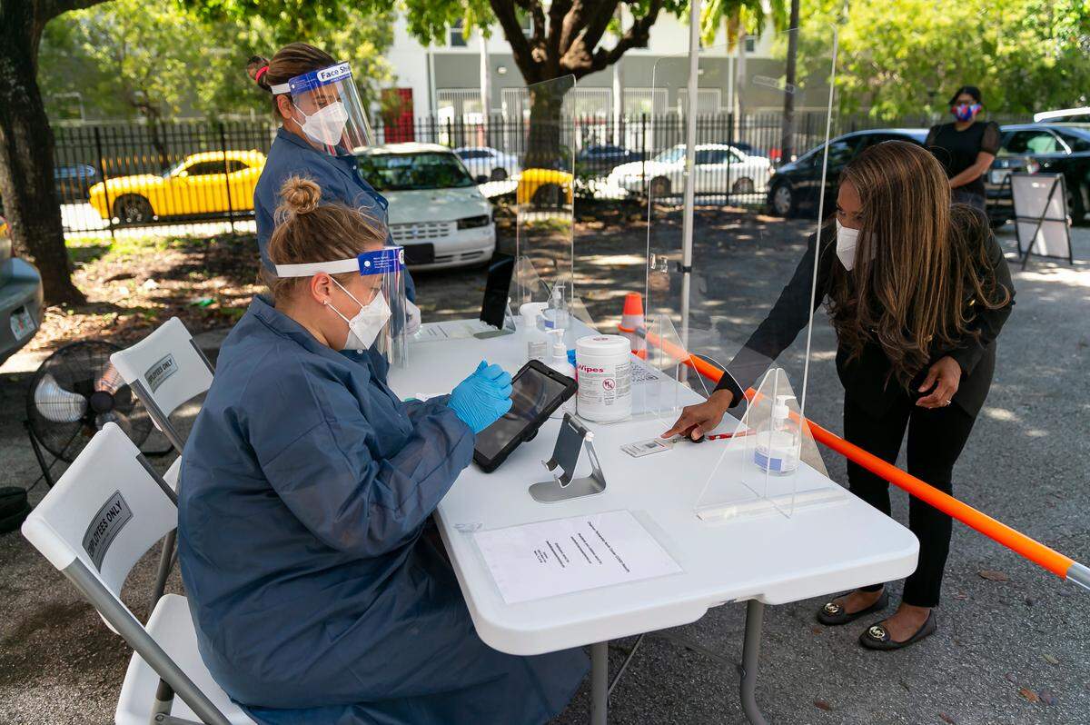 Symeria Hudson, the president and CEO of Chapman Partnership, shows identification before taking a Curative COVID-19 PCR test at the nonprofit’s parking lot in downtown Miami. Through strict COVID protocols, she’s kept the COVID positivity rate at Chapman to under 3 percent.