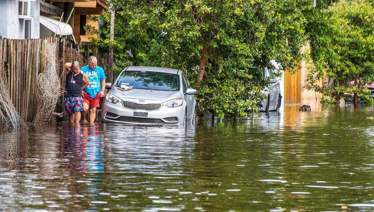 Two men walk through the flood at West 14th Avenue and West 29th Street in Hialeah as torrential downpours inundate South Florida due to a disturbance off Florida’s coast on Thursday, November 16, 2023.