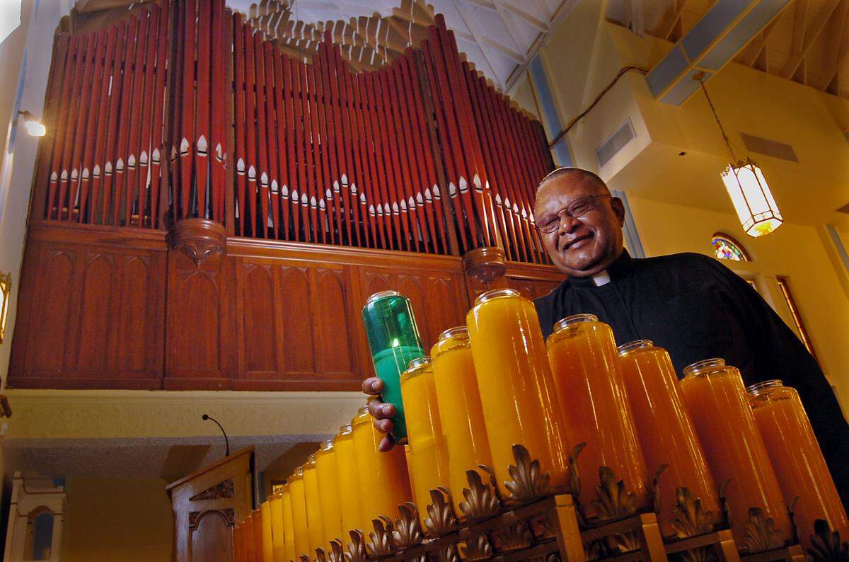The pipe organ at the Historic Saint Agnes Episcopal Church in Overtown. The Rev. Dr. Richard L. Marquess-Barry places one of the candles with the organ behind him in this 2006 file photo. The restored organ has over 2,000 pipes.