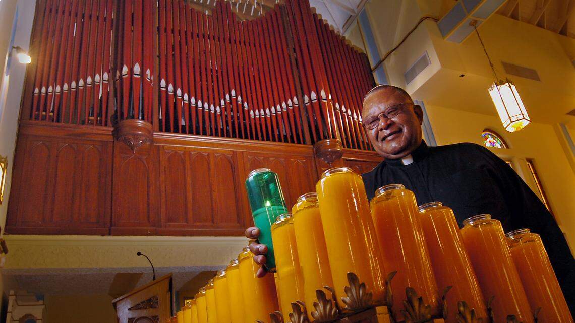The pipe organ at the Historic Saint Agnes Episcopal Church in Overtown. The Rev. Dr. Richard L. Marquess-Barry places one of the candles with the organ behind him in this 2006 file photo. The restored organ has over 2,000 pipes.