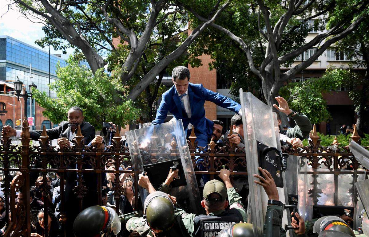 Venezuelan opposition leader Juan Guaidó climbs a fence to reach the National Assembly building in Caracas on Jan. 5.