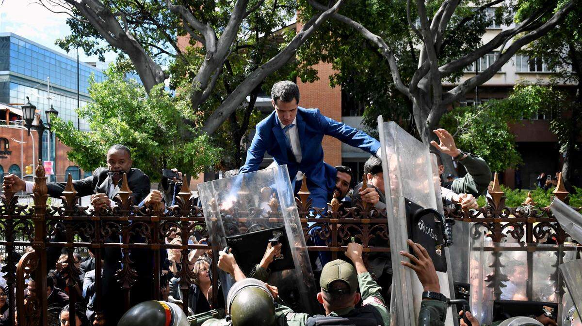 Venezuelan opposition leader Juan Guaidó climbs a fence to reach the National Assembly building in Caracas on Jan. 5.