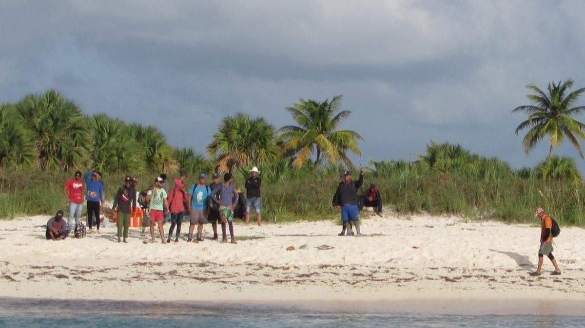 More than 20 Cubans stand on a Cay Sal Bank beach in the Bahamas Wednesday, Oct. 28, 2020. They had been stranded there for 10 days, according to the U.S. Coast Guard.
