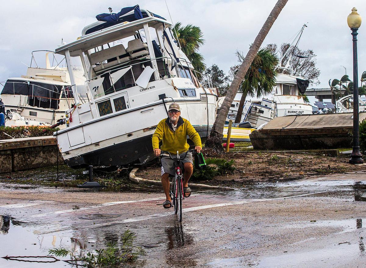 A biker rides past large boats displaced onto the ground in Legacy Harbour Marina Thursday, Sept. 29, 2022, the day after Hurricane Ian hit Fort Myers Beach as a Category 4 storm.