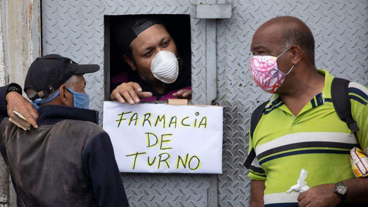 Sign tells two Venezuelan men that a pharmacist is on duty.