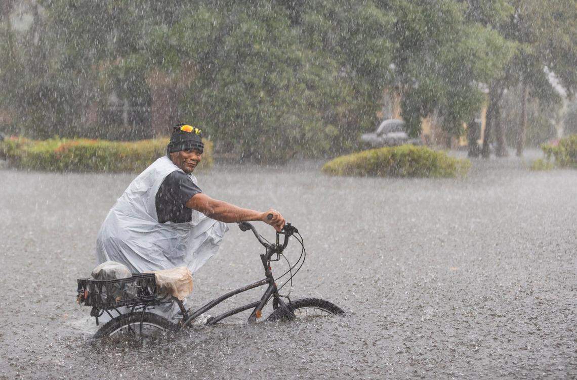 Leon rides his bike down a flooded street in the Edgewood neighborhood on Thursday, April 13, 2023, in Fort Lauderdale, Fla. A torrential downpour severely flooded streets partially submerging houses and cars across South Florida.