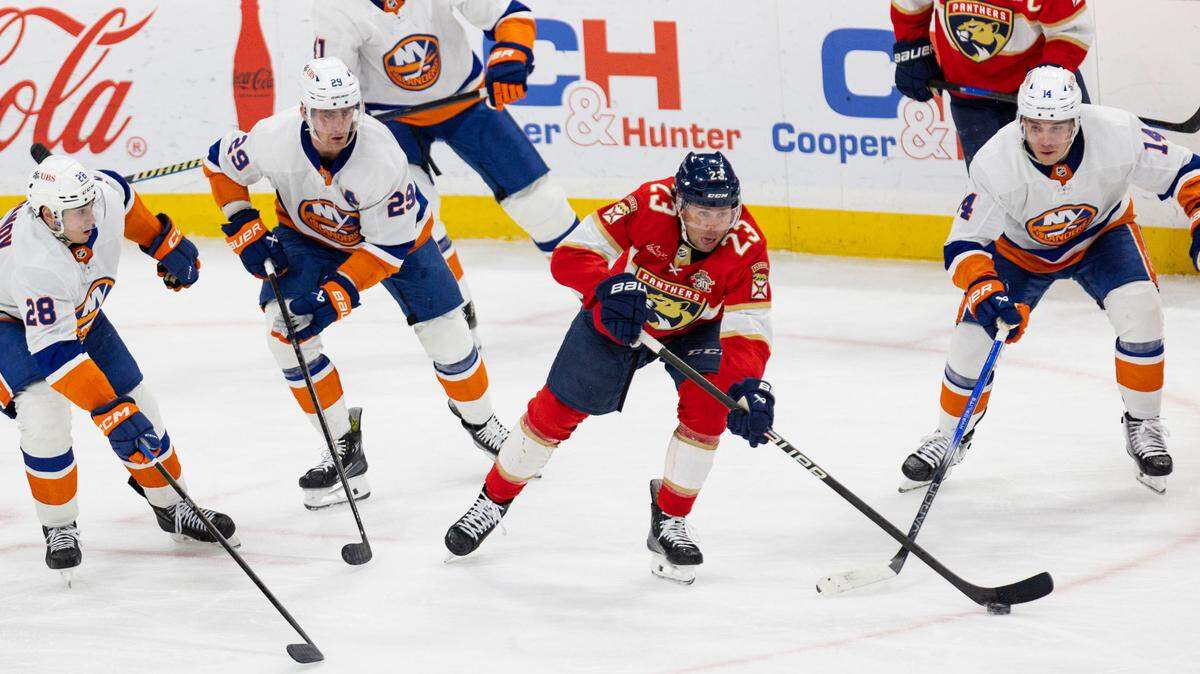 Florida Panthers center Carter Verhaeghe (23) passes around New York Islanders defenseman Alexander Romanov (28), center Brock Nelson (29), center Bo Horvat (14) during the third period of a game on Thursday, March 28, 2024, at Amerant Bank Arena in Sunrise, Fla. The New York Islanders won 3-2.