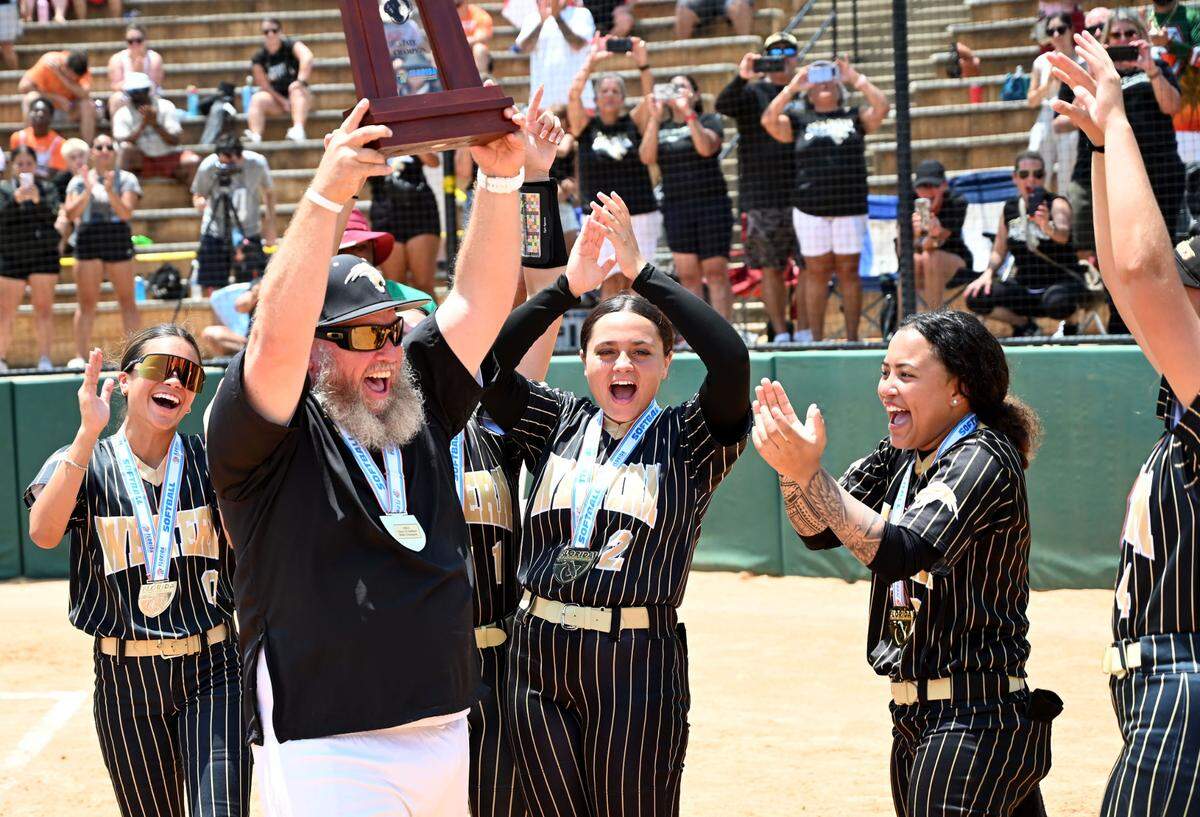 Western head coach John Bradshaw holds up the Class 7A softball state championship trophy at the FHSAA Finals on Saturday at Legends Way Ballfields in Clermont, Fla.