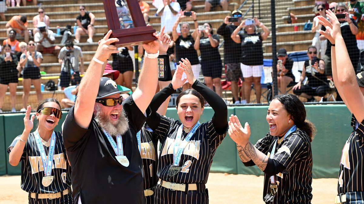 Western head coach John Bradshaw holds up the Class 7A softball state championship trophy at the FHSAA Finals on Saturday at Legends Way Ballfields in Clermont, Fla.