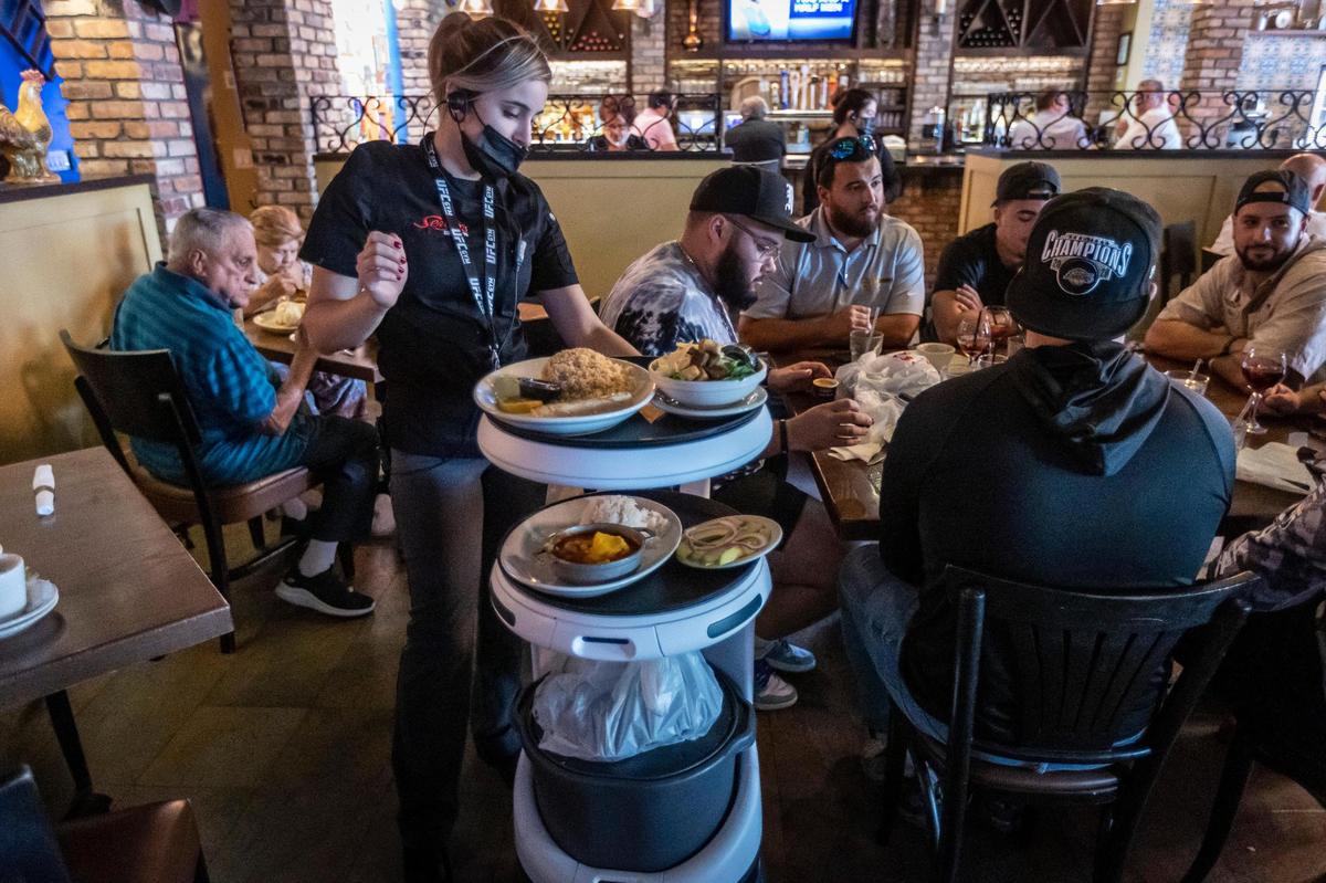 A waitress at Sergio’s takes control of the Servi robot, known as ASTRO, and steers it manually using the keyboard to guide it around a spot it can’t get through because a diner inadvertently blocked its path with his chair.