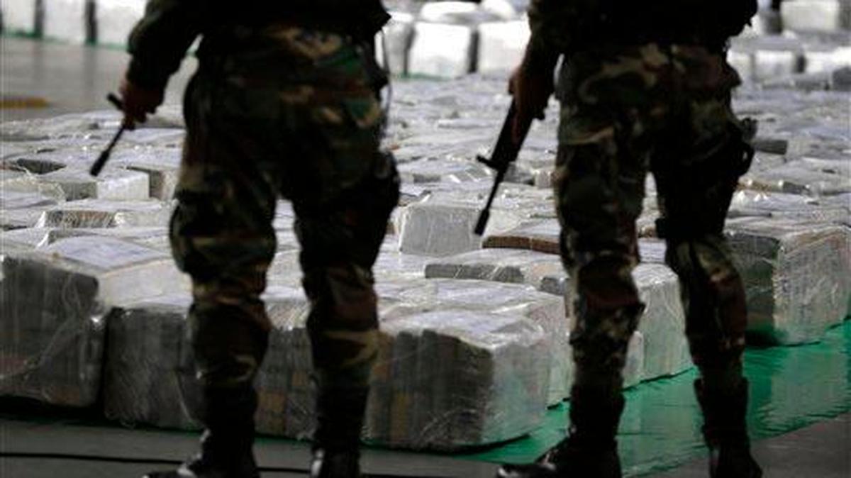 In this Sept. 1, 2014, file photo, police officers stand guard over seized cocaine they present to the press in Lima, Peru. The packages are part of a 7.7 metric ton seizure made in the northern city of Trujillo on Aug. 26, the largest in Peru’s history. Peru is the world's leading producer of cocaine, according to the DEA. (AP Photo/Martin Mejia, File)