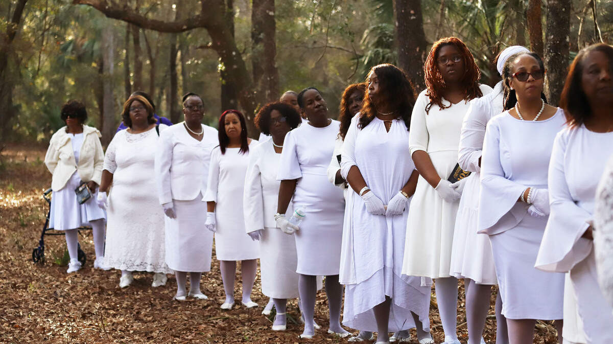 The descendants of the Rosewood massacre stand along the railway during the wreath-laying ceremony at Rosewood, Fla., Sunday, Jan.8, 2023.