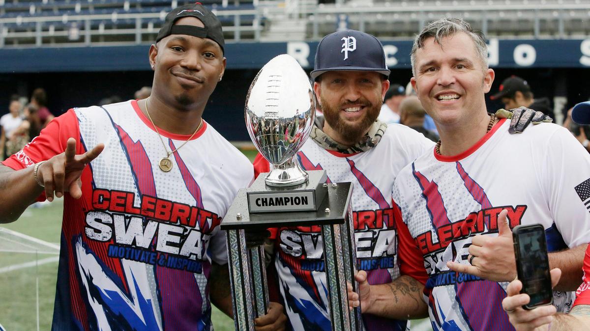 Team Flutie members (from left) Kris Lofton, actor; Preston Brust, musician; and Sgt. First Class Dann Rogers hold a trophy after their team won against Team McNabb during the 20th annual Super Bowl Celebrity Flag Football Challenge on Saturday at FIU.