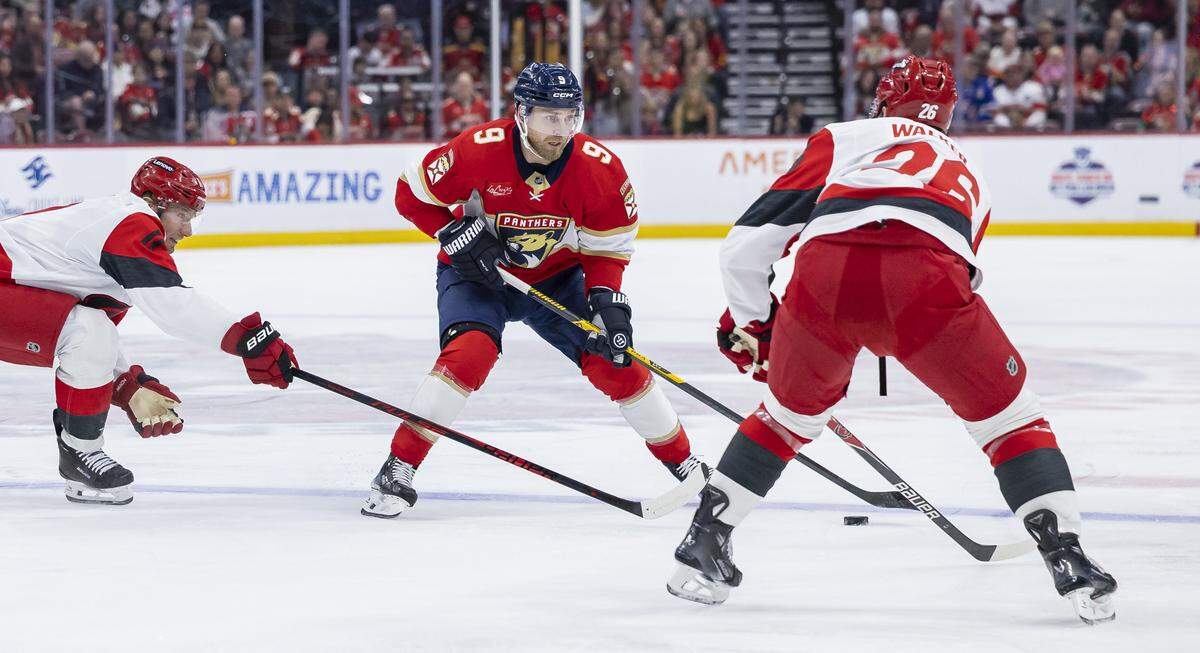 Florida Panthers center Sam Bennett (9) looks to pass the puck as Carolina Hurricanes defenseman Sean Walker (26) defends in the first period of their NHL game at Amerant Bank Arena on Friday, Dec. 19, 2025, in Sunrise, Fla.