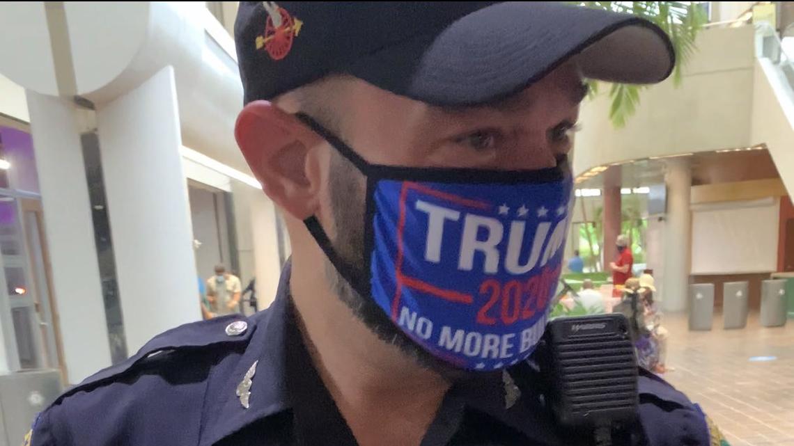 A uniformed Miami police officer pictured wearing a protective mask with a pro-Trump slogan at a voting site in Government Center in October, has been suspended as police investigate a hand signal he made that is allegedly related to the white power movement. He denies it.