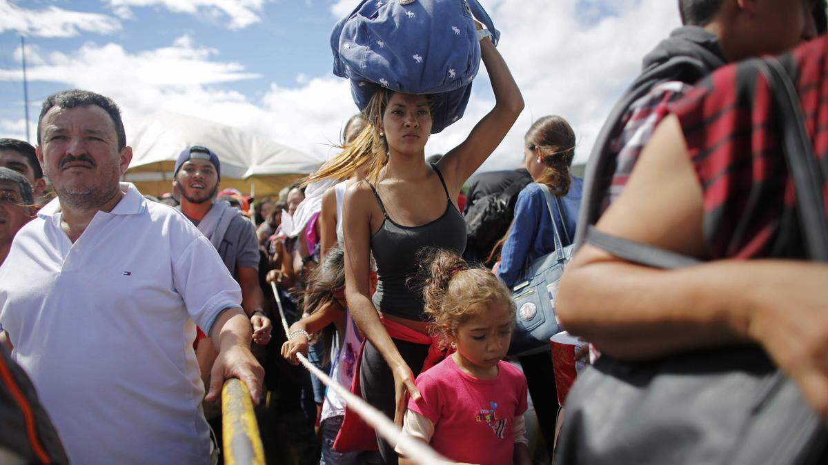 A woman carrying a bundle on her head waits in line in 2016 to cross the border into Colombia through the Simon Bolivar International Bridge in San Antonio del Tachira, Venezuela, joining thousands of Venezuelans who crossed the border into Colombia each day.