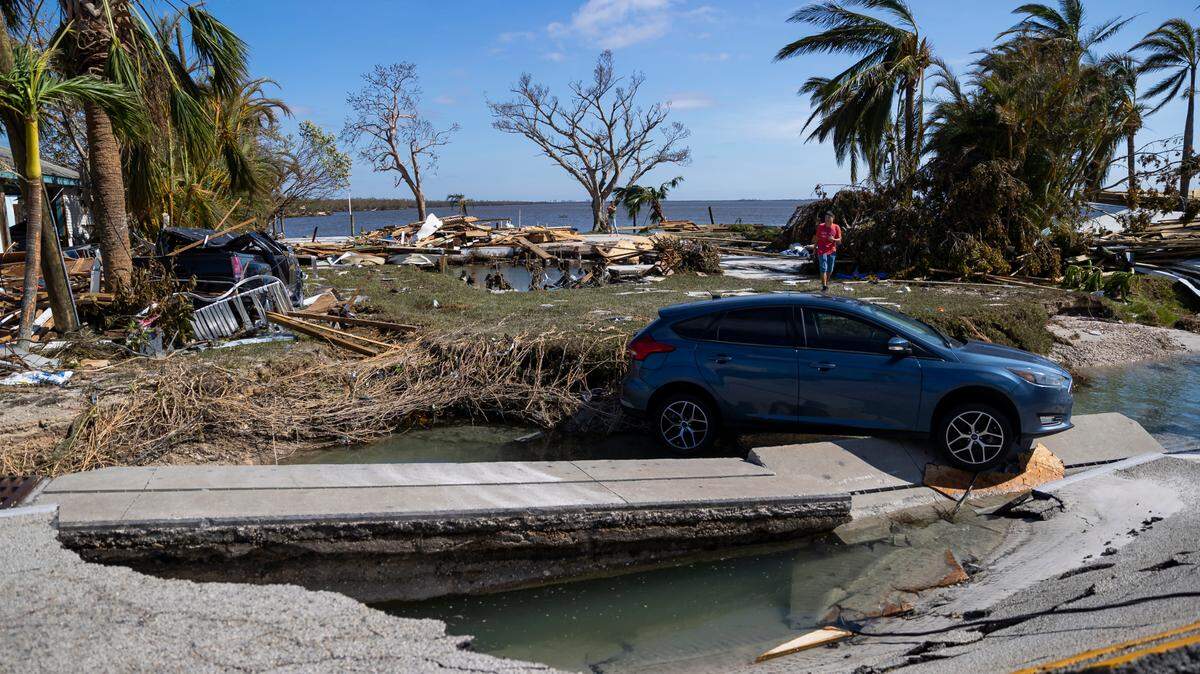 A blue ford focus is seen balanced over broken concrete and land on Pine Island Road on Thursday, Sept. 29, 2022, in Matlacha, Fla. Hurricane Ian made landfall on the coast of South West Florida as a category 4 storm Tuesday afternoon leaving areas affected with flooded streets, downed trees and scattered debris.