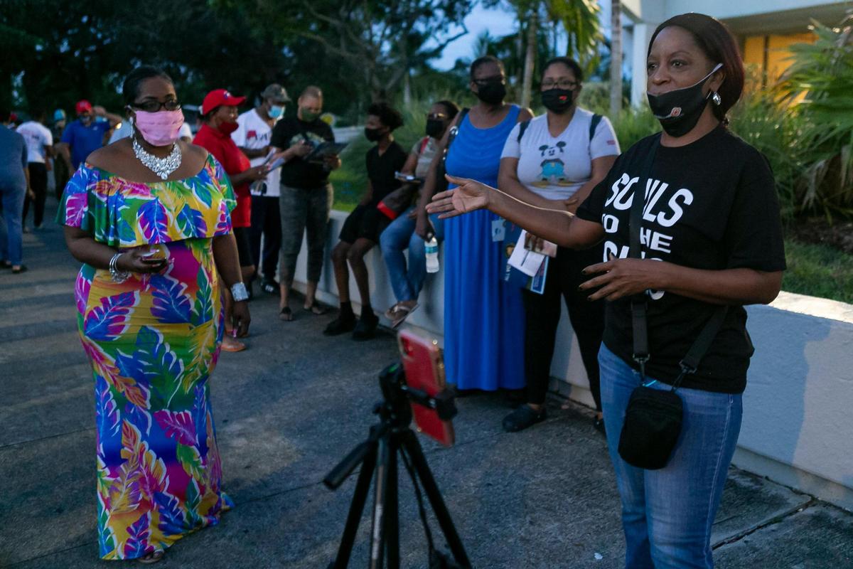 Pastor Stephanie E. Russell, right, and Denise Mills Mincey, left, pray as voters lineup to cast their early ballots at the North Dade Regional Library in Miami Gardens on Saturday, October 24, 2020. Faith in Florida, a federation of the national faith-based grassroots organization Faith in Action, hosted Prayer at the Polls events like this one across the state Saturday.