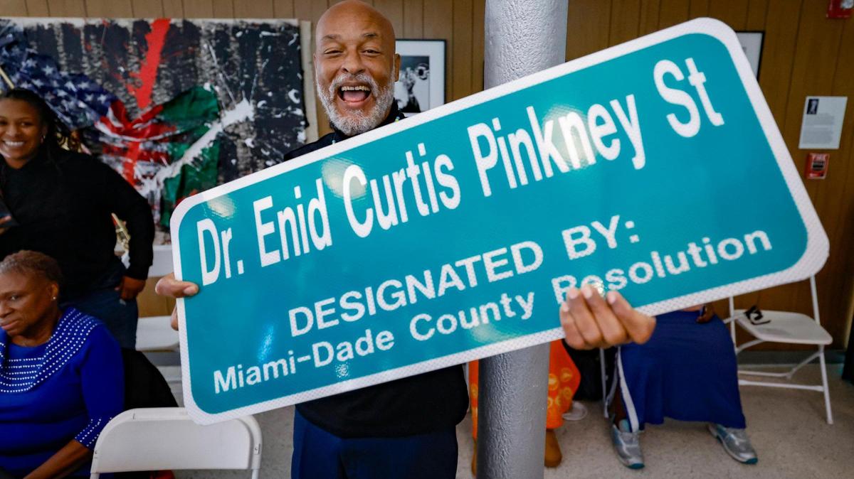 Gary Allen, holds a street sign during the street naming ceremony for his aunt, Dr. Enid Curtis-Pinkney.