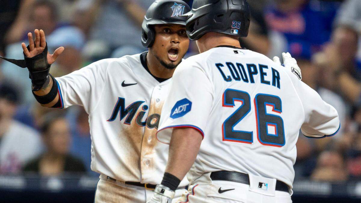 Miami Marlins base runner Garrett Cooper (26) reacts with teammate Luis Arraez (3) after hitting a home run during the sixth inning of an MLB game against the New York Mets at LoanDepot Park in Miami, Florida, on Thursday, March 30, 2023.