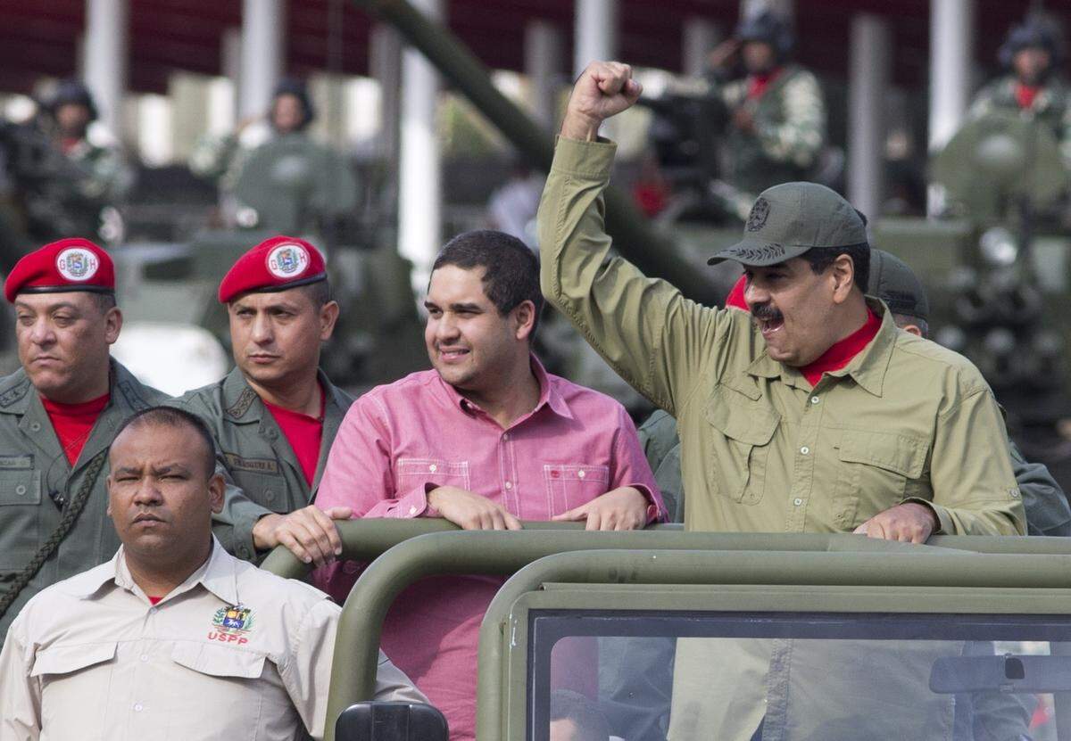 Accompanied by his son Nicolás, Venezuela's President Nicolás Maduro raises a fist as he arrives at a military parade in Caracas on Friday, April 13, 2018.