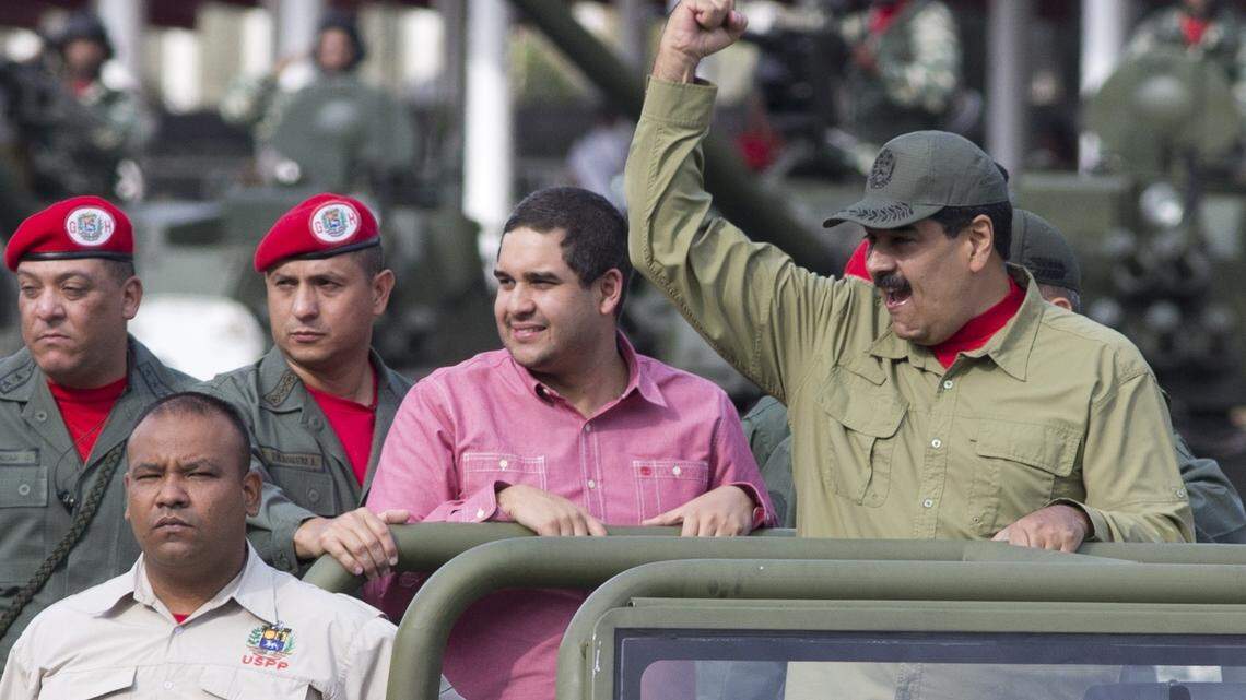 Accompanied by his son Nicolás, Venezuela's President Nicolás Maduro raises a fist as he arrives at a military parade in Caracas on Friday, April 13, 2018.