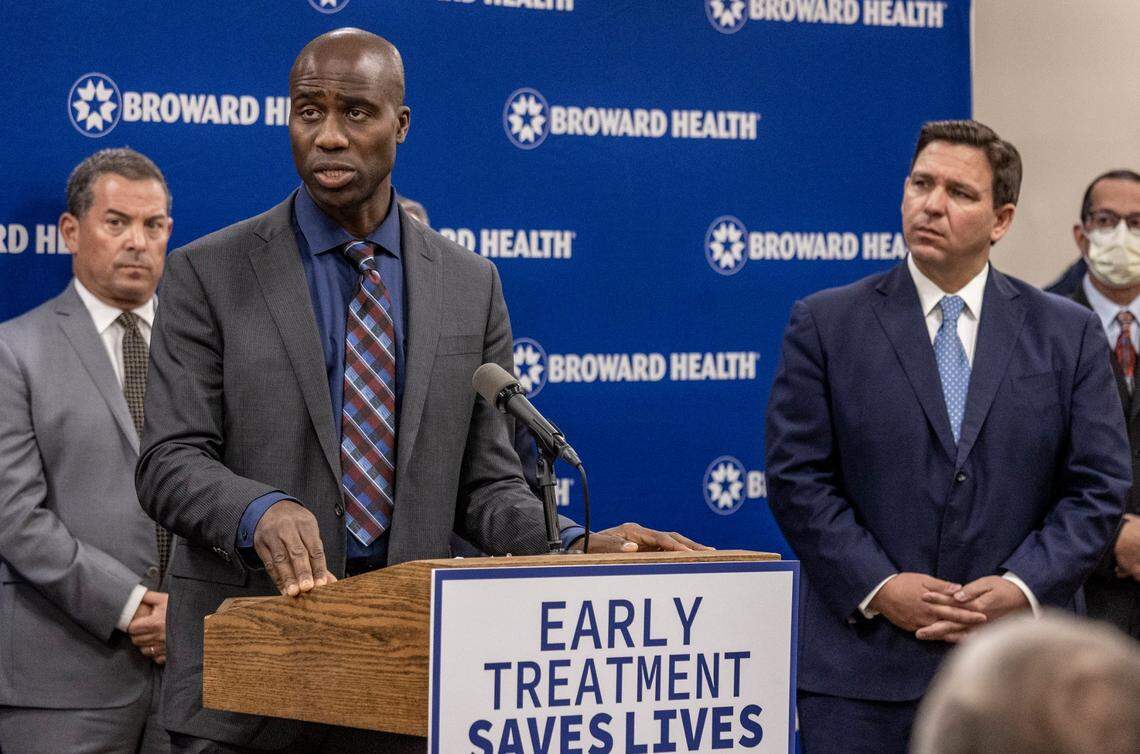 Florida Surgeon General, Joseph Ladapo, left, speaks during a press conference at Broward Health Medical Center on Jan. 3, 2022, as Gov. Ron DeSantis , right, listens.