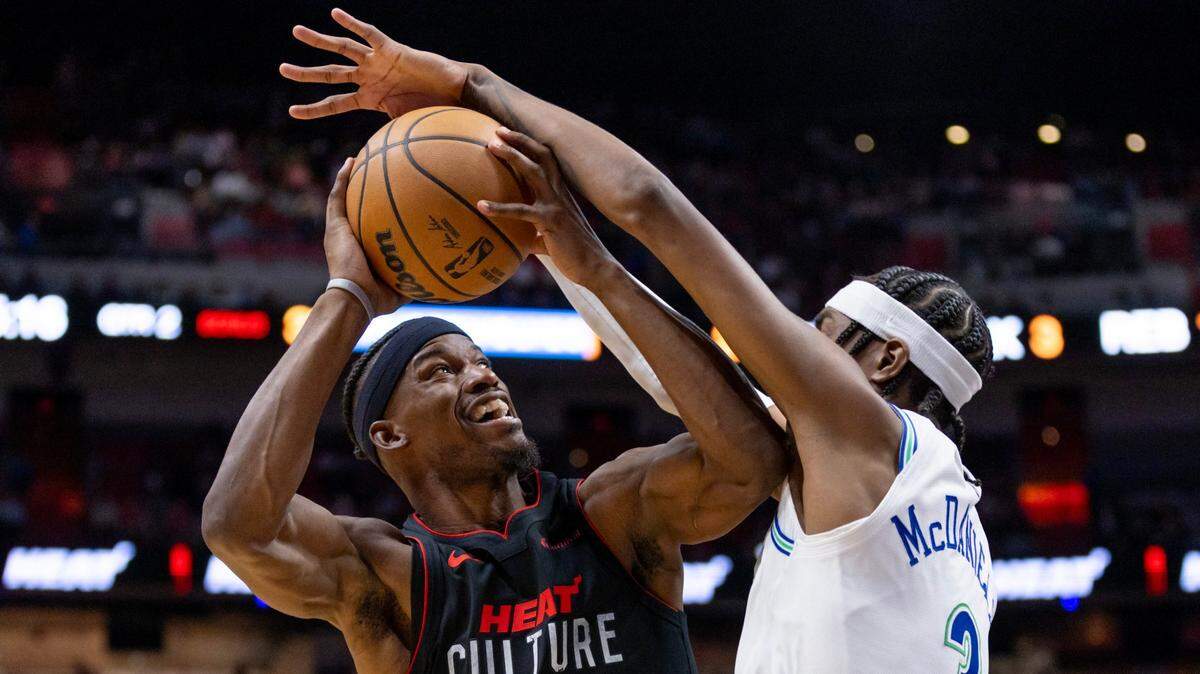 El delantero del Heat Jimmy Butler (izq.) trata de anotar ante la marca de Jaden McDaniels, de los Timberwolves de Minnesota, en el partido celebrado el 18 de diciembre de 2023 en Miami.