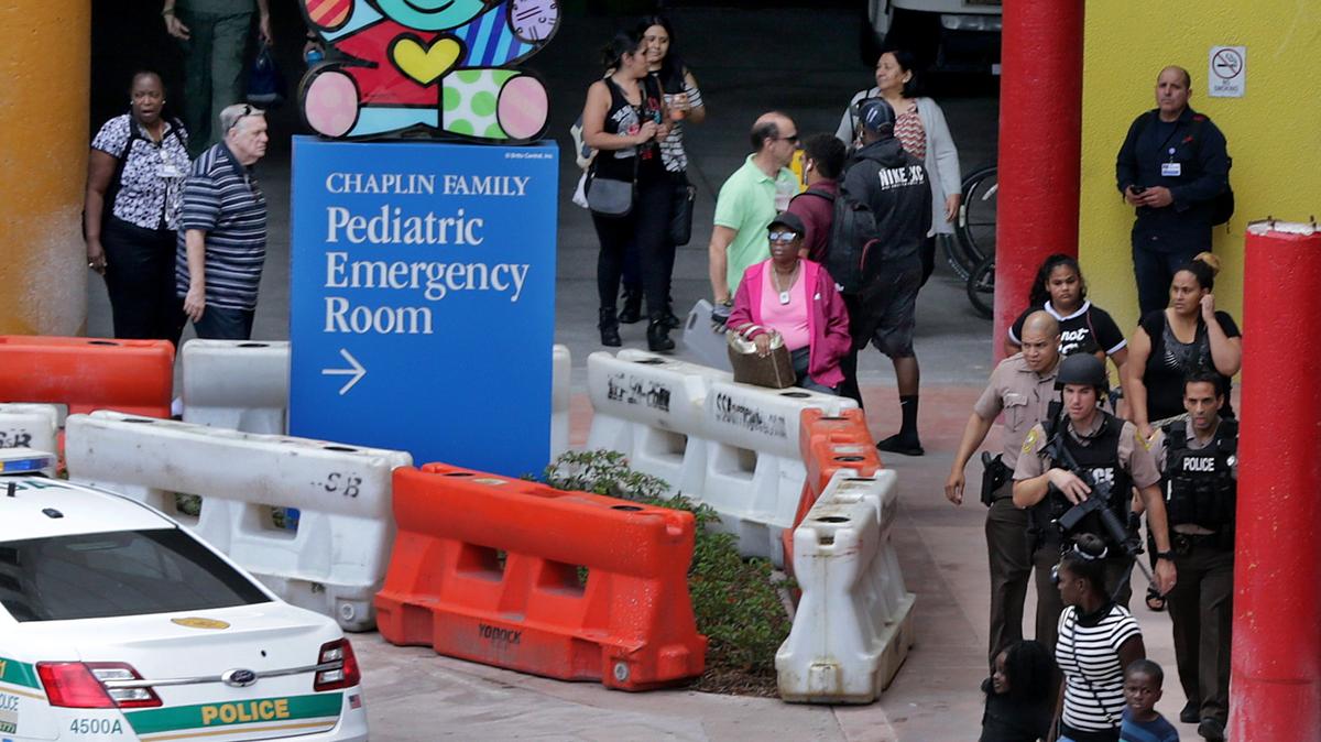 Miami Dade Police Department officers walk along visitors and employees after they have detained one person after a phoned threat caused a swarm of police activity at Jackson Memorial Hospital for about an hour Friday afternoon, on Friday, June 29, 2018.